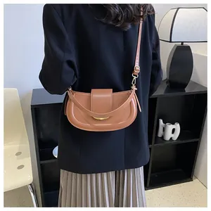 Brown leather saddle bag with gold metal buckle shown on model in stylish room