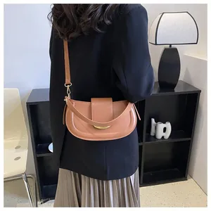 Close-up of caramel brown saddle bag featuring gold hardware and adjustable strap detail