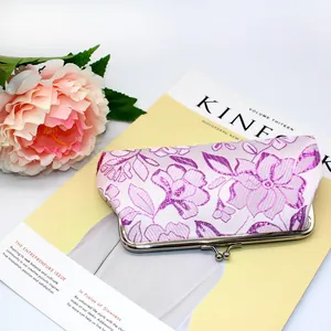 Detailed view of lavender satin fabric with floral embroidery and golden kiss-lock clasp