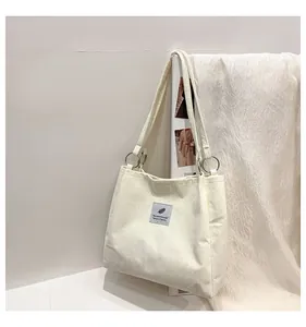 Detail of off-white corduroy tote bag showing vertical texture and silver ring metal hardware