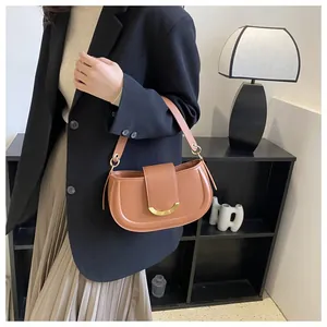 Close-up of brown leather saddle bag featuring a bold U-shaped gold metal buckle detail