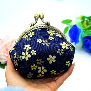 Detailed view of hand-held Japanese style fabric coin purse with gold sakura pattern