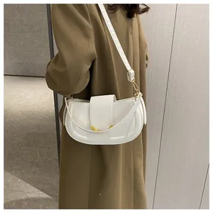 Detailed view of a white semi-circle underarm bag with an elegant golden V-shaped buckle
