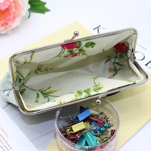 Detail view of mint green floral embroidery wallet with silver kiss lock and floral lining