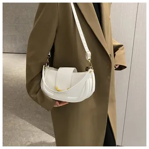 Detail of white saddle bag with golden crescent buckle and versatile double straps