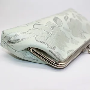 Close-up of floral jacquard fabric and silver metal frame on a mint green vintage clutch