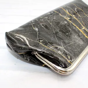 Close-up of marble pattern purse with silver kiss-lock clasp and glossy finish texture