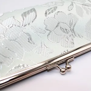 Close-up of floral jacquard fabric and polished silver kiss-lock on long wallet