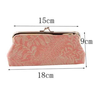 Detail showing coral pink leaf patterns and metal kiss lock buckle on a fabric purse