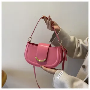 Detailed view of a pink crescent saddle bag with gold buckle and adjustable strap