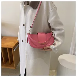 Detailed view of pink leather saddle bag with gold metal buckle and adjustable strap