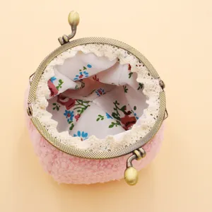 Détail du porte-monnaie en peluche rose avec fermoir bronze, doublure florale et dentelle