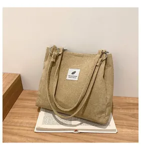 Detail of khaki corduroy tote bag showing vertical texture and white graphic patch