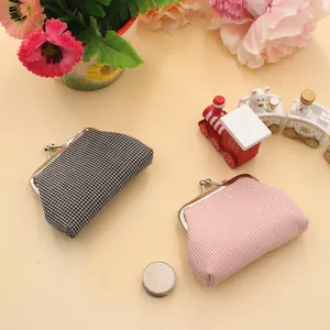 Close-up van vintage mini geruite portemonnees met zilveren metalen sluitingen op beige