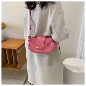 Side view of a model wearing a pink saddle bag with a golden crescent buckle closure