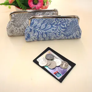 Close-up of canvas leaf pattern coin purses with silver metal clasps and bank cards