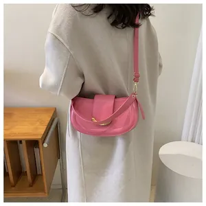 Detailed back view of a pink hobo bag with gold buckle on a model in a minimalist room