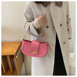 Detailed view of pink leather saddle bag featuring a distinctive gold crescent buckle