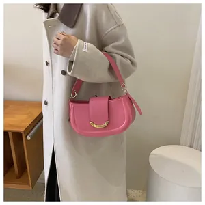 Detail of light pink crescent saddle bag with gold buckle on a beige coat