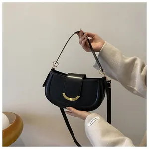 Macro detail of black saddle bag with glossy leather texture and gold hardware buckle