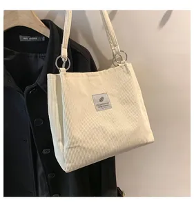 Close-up of cream corduroy tote bag featuring vertical texture and silver metal ring hardware