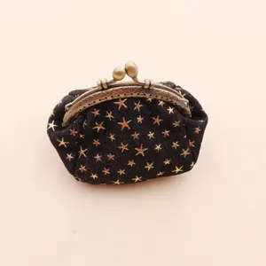 Detail of vintage denim kiss-lock coin purse with golden star pattern and bronze clasp