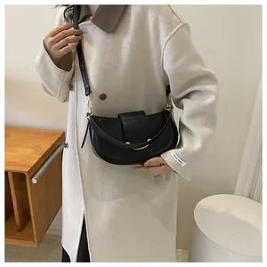 Detail of minimalist black saddle bag featuring gold metal hardware and matte leather texture