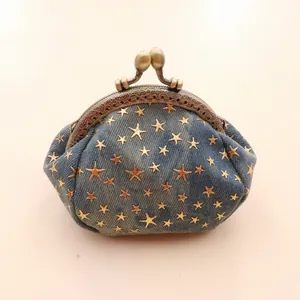 Macro detail of star pattern denim coin purse with vintage engraved bronze kiss lock frame