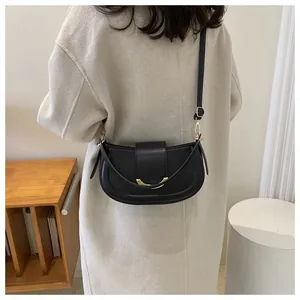 Rear view of model wearing a black crescent saddle bag with gold hardware details