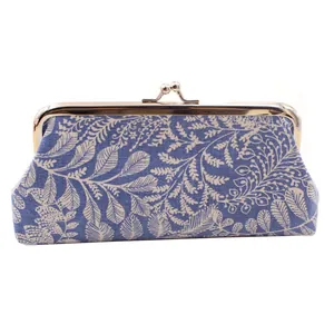 Detail of blue fabric kiss-lock coin purse with white leaf pattern and gold metal clasp