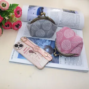 Close-up of vintage kiss-lock canvas coin purses with floral leaf patterns and a phone case