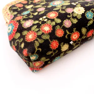 Close-up of vintage floral embroidery fabric and golden kiss lock frame on a coin purse
