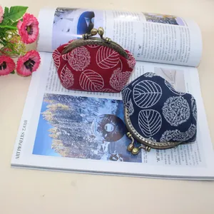 Close-up of vintage canvas clasp purses with white leaf embroidery and metal frames