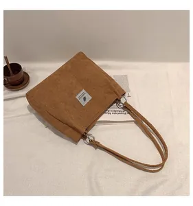 Detail of brown corduroy tote bag showing fabric texture and metal ring strap connector