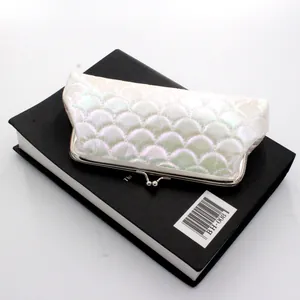 Detail of holographic fish scale texture and silver metal clasp on the white clutch bag