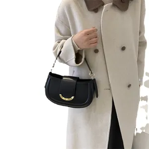 Classic black saddle underarm bag with gold metal buckle shown on a model