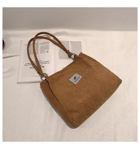 Detail of brown corduroy tote bag showing striped texture and gray fabric patch