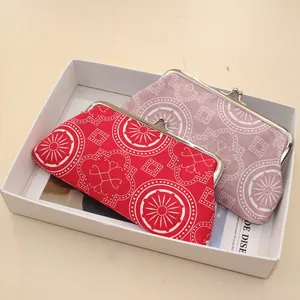 Detail of red and pink fabric purses with white geometric patterns and silver metal clasps