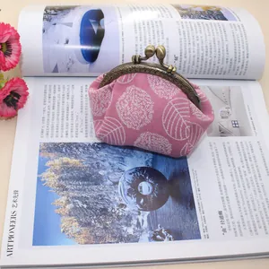 Detail of leaf embroidery on pink canvas frame purse with large pearl clasp on magazine