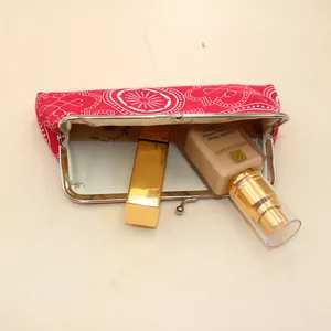 Detail of red fabric cosmetic bag with geometric patterns and metal clasp opening