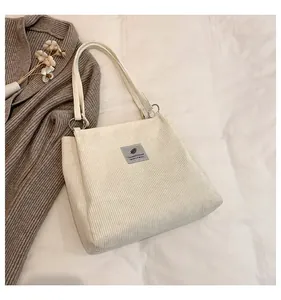 Close-up of cream corduroy tote bag featuring a textured finish and grey fabric logo patch