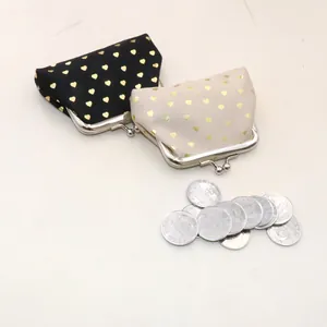 Detail showing two fabric coin purses with gold heart patterns and metal clasps with coins