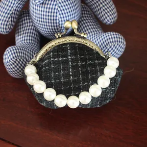 Detail van de 10,5cm tweed tas met bronzen sluiting en een elegante parel handgreep