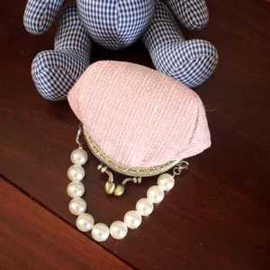 Detail van roze tweed portemonnee met vintage metalen sluiting en parelhandvat