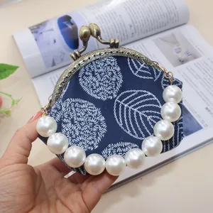Detail of leaf embroidery on blue canvas with vintage metal frame and pearl handle