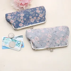 Detail view of vintage floral fabric coin purses with metal clasps and cards as size reference