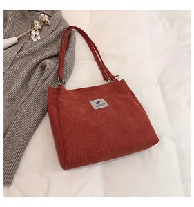 Flat lay of a brown corduroy tote bag with fabric label on a soft aesthetic background