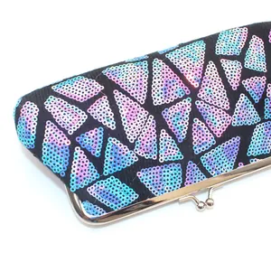Makroaufnahme geometrischer Pailletten und silbernem Klickverschluss an einer Clutch