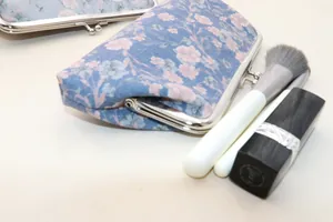 Detail of floral fabric wallets with vintage metal clasps in a set of two light blue pouches