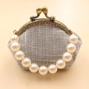 Detail van tweed portemonnee met vintage bronzen sluiting en elegante parelhengsel